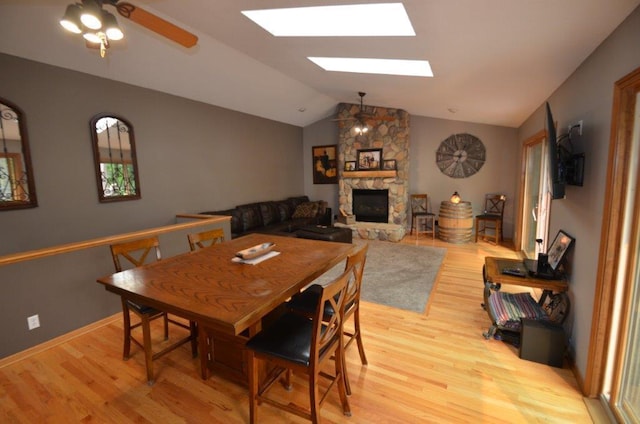 12207 285th St, Lindstrom, MN 55045 - dining area with a skylight, light wood-style floors, a ceiling fan, a fireplace, and vaulted ceiling