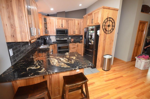 12207 285th St, Lindstrom, MN 55045 - kitchen featuring stainless steel appliances, tasteful backsplash, a peninsula, dark countertops, and glass insert cabinets