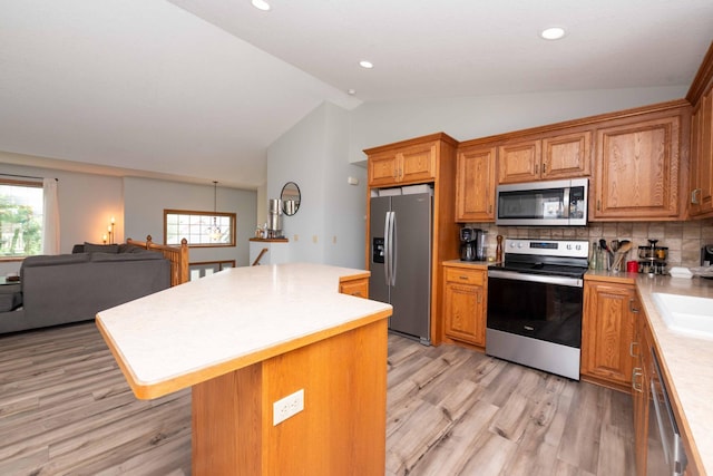 1406 English Ave NW, New Prague, MN 56071 - kitchen featuring appliances with stainless steel finishes, vaulted ceiling, light wood-style floors, light countertops, and a center island