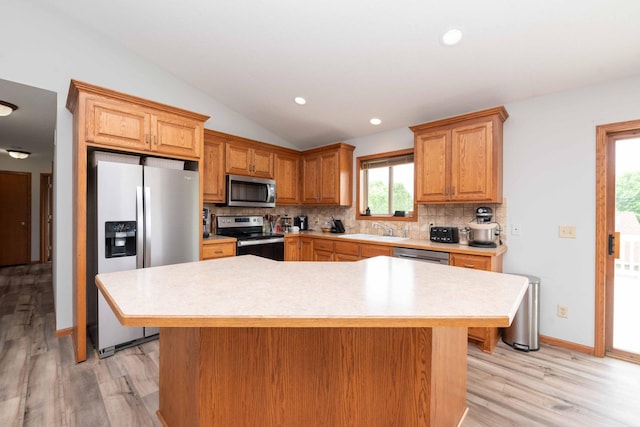 1406 English Ave NW, New Prague, MN 56071 - kitchen with stainless steel appliances, vaulted ceiling, tasteful backsplash, light countertops, and light wood-style flooring