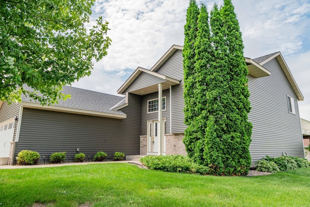 1406 English Ave NW, New Prague, MN 56071 - view of front of property featuring a front yard, an attached garage, brick siding, and a shingled roof