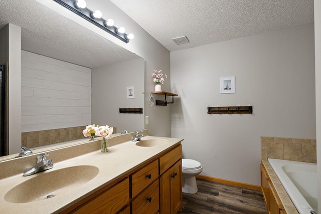 7331 Lamont Ave NE, Otsego, MN 55301 - bathroom featuring wood finished floors, a bath, double vanity, and a textured ceiling