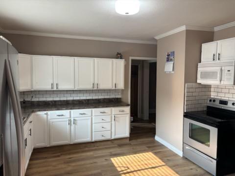 664 12th St, Windom, MN 56101 - kitchen featuring stainless steel appliances, backsplash, white cabinets, ornamental molding, and wood finished floors
