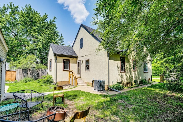 3807 Hubbard Ave N, Robbinsdale, MN 55422 - rear view of house with stucco siding, entry steps, an outdoor fire pit, and a shingled roof