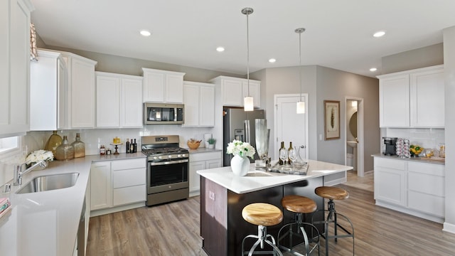1064 Aster Blvd, Rosemount, MN 55068 - kitchen featuring appliances with stainless steel finishes, decorative backsplash, a sink, light wood-type flooring, and white cabinetry