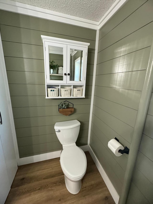 8339 71st St, West Concord, MN 55985 - bathroom featuring toilet, wood finished floors, a textured ceiling, wood walls, and baseboards