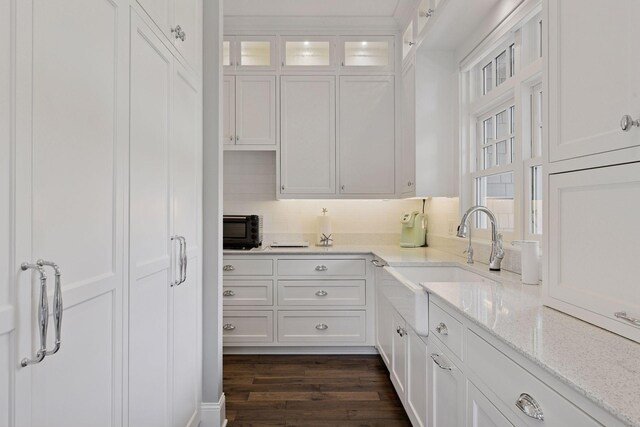 3758 Woodland Cove Pkwy, Minnetrista, MN 55331 - kitchen featuring white cabinetry, light stone countertops, glass insert cabinets, dark wood-type flooring, and tasteful backsplash