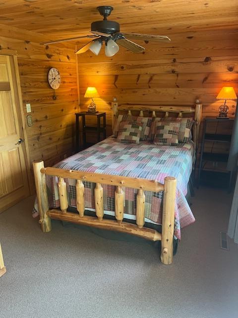 6543 Point Dr, Ideal Twp, MN 56474 - carpeted bedroom with wood walls and ceiling fan