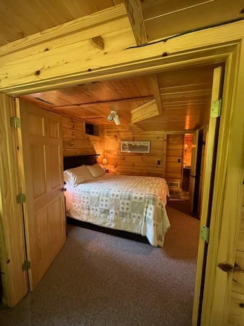 6543 Point Dr, Ideal Twp, MN 56474 - bedroom with wooden ceiling, wooden walls, and dark colored carpet