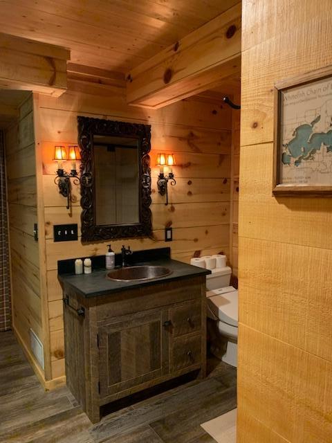 6543 Point Dr, Ideal Twp, MN 56474 - bathroom with wooden walls, wood ceiling, wood finished floors, vanity, and toilet