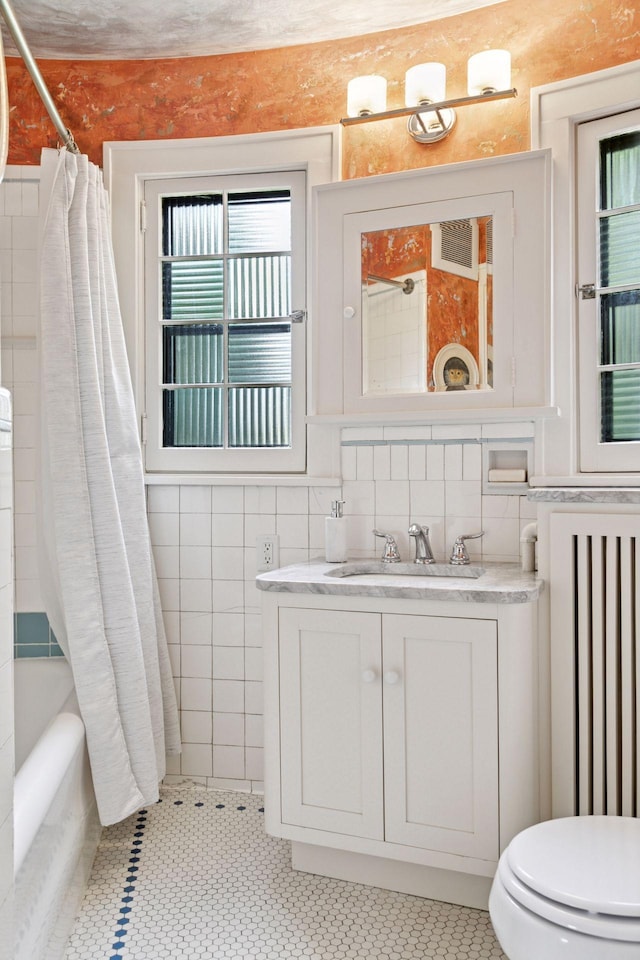 2248 Goodrich Ave, Saint Paul, MN 55105 - bathroom featuring vanity, toilet, shower / bath combo with shower curtain, tile walls, and radiator