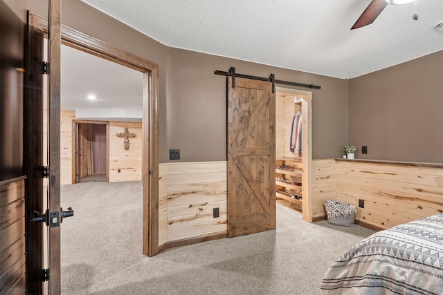 4027 148th Ln NE, Ham Lake, MN 55304 - bedroom with carpet, a barn door, wood walls, wainscoting, and ceiling fan
