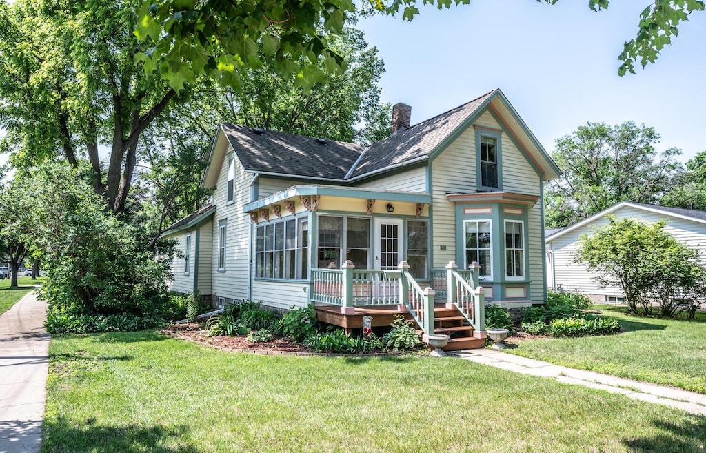 320 Walnut St, Farmington, MN 55024 - victorian home featuring a chimney, a sunroom, a front yard, and roof with shingles