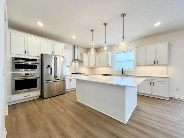 9901 49th St NE, Saint Michael, MN 55376 - kitchen featuring appliances with stainless steel finishes, light wood-style flooring, wall chimney range hood, a kitchen island, and recessed lighting