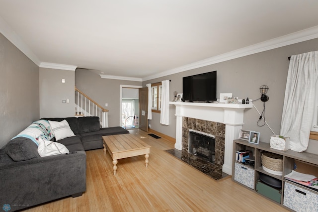 1345 4th St N, Fargo, ND 58102 - living room featuring stairway, wood finished floors, a tiled fireplace, and ornamental molding