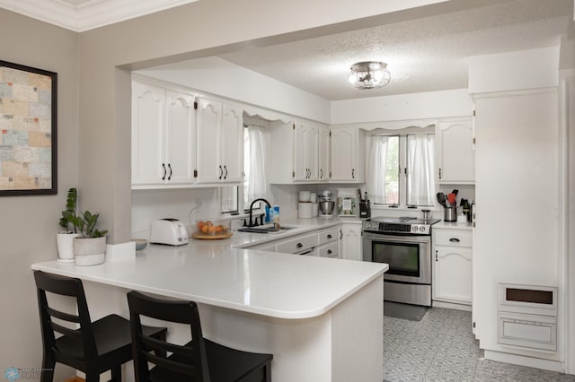 1345 4th St N, Fargo, ND 58102 - kitchen with stainless steel electric range, a sink, a peninsula, a kitchen bar, and white cabinetry