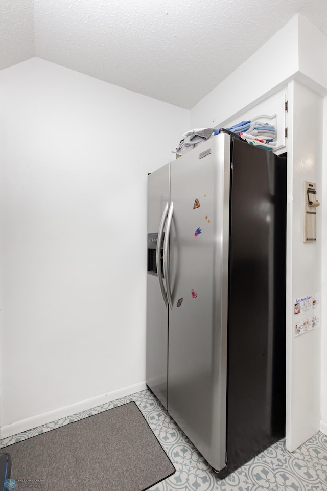 1345 4th St N, Fargo, ND 58102 - kitchen with stainless steel fridge, white cabinetry, a textured ceiling, baseboards, and vaulted ceiling