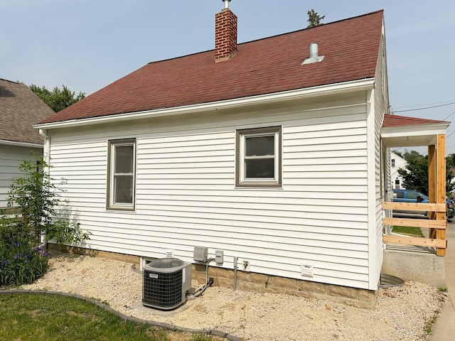 951 13th Ave NE, Rochester, MN 55906 - view of side of home featuring central AC, a chimney, and roof with shingles