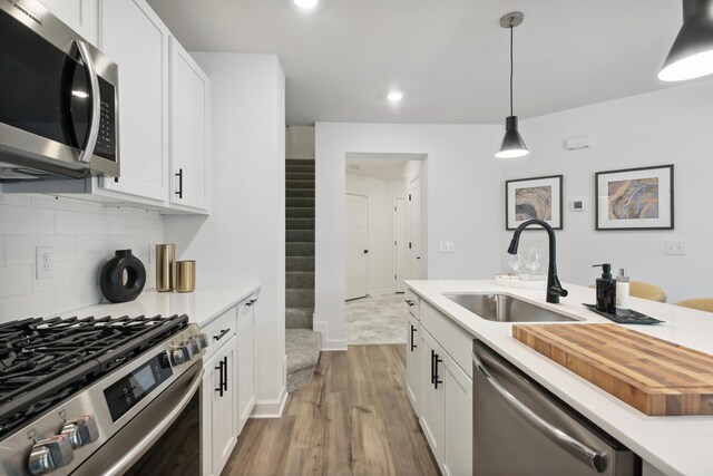 14964 Gibbon Ter NW, Ramsey, MN 55303 - kitchen featuring stainless steel appliances, a sink, wood finished floors, white cabinetry, and light countertops