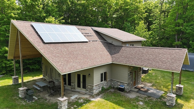 4251 Sugar Pt, Orr, MN 55771 - view of front of home with french doors, stone siding, a shingled roof, a front yard, and solar panels