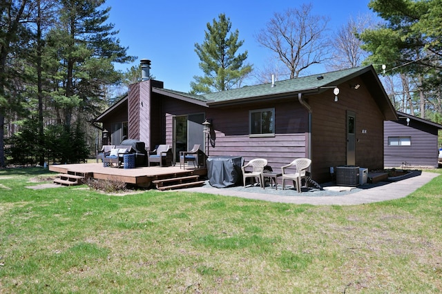 10151 Sandy Beach Rd, Round Lake Twp, WI 54843 - rear view of property featuring a chimney, a deck, a lawn, and central AC unit