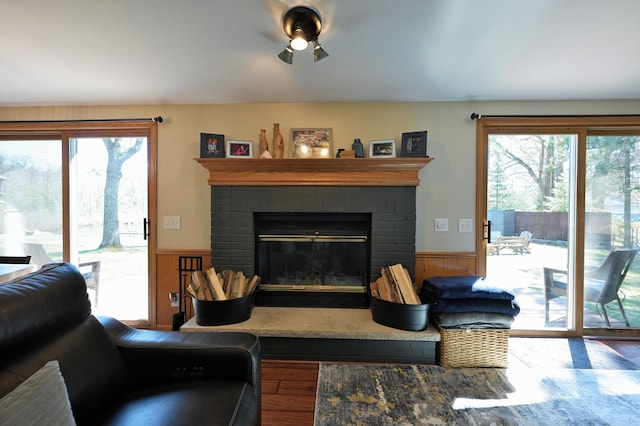 10151 Sandy Beach Rd, Round Lake Twp, WI 54843 - living area with wood finished floors, a wainscoted wall, a ceiling fan, a brick fireplace, and wooden walls