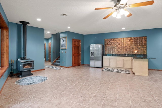 2207 Barron Polk St, Comstock, WI 54826 - kitchen with stainless steel fridge, a wood stove, ceiling fan, light tile patterned flooring, and baseboards