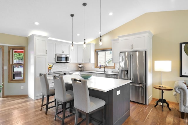 5630 Oak View Ct, Savage, MN 55378 - kitchen with appliances with stainless steel finishes, white cabinetry, lofted ceiling, backsplash, and a center island