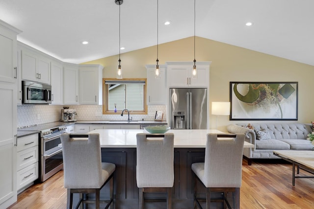 5630 Oak View Ct, Savage, MN 55378 - kitchen with appliances with stainless steel finishes, lofted ceiling, a kitchen bar, light wood finished floors, and tasteful backsplash