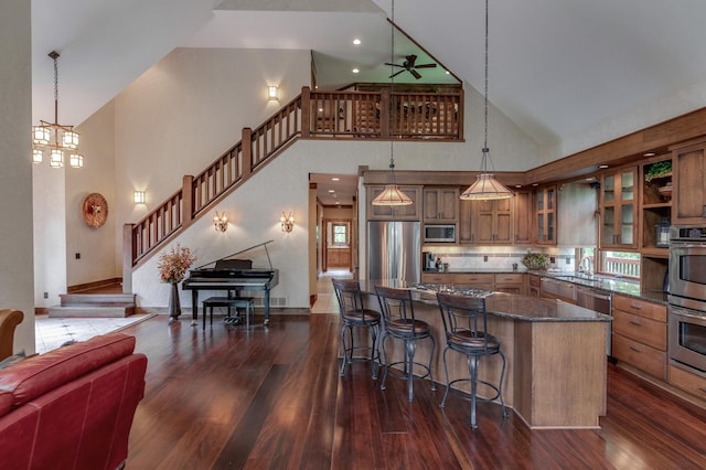 31839 Cree Bay Cir, Pelican Twp, MN 56472 - kitchen with stainless steel appliances, high vaulted ceiling, brown cabinetry, dark wood-style floors, and a kitchen bar