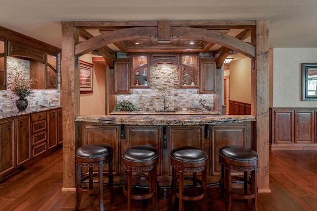 31839 Cree Bay Cir, Pelican Twp, MN 56472 - indoor wet bar featuring arched walkways, decorative backsplash, dark wood-type flooring, and wainscoting