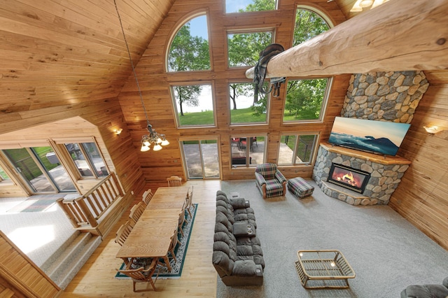 6031 232nd St W, Faribault, MN 55021 - living room featuring high vaulted ceiling, wooden walls, plenty of natural light, a stone fireplace, and a chandelier