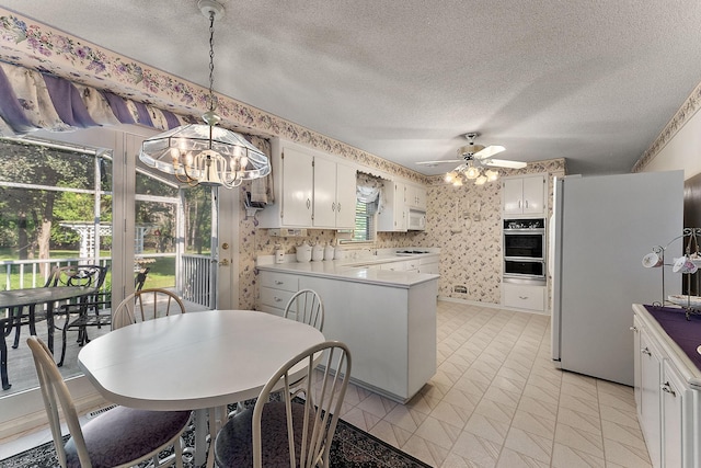 6379 Hodgson Rd, Lino Lakes, MN 55014 - kitchen featuring white appliances, wallpapered walls, a warming drawer, a chandelier, and a peninsula