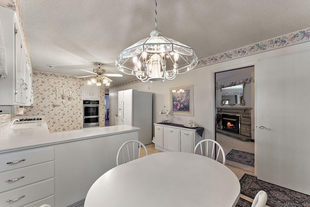 6379 Hodgson Rd, Lino Lakes, MN 55014 - dining space featuring a lit fireplace, a textured ceiling, ceiling fan, and a chandelier