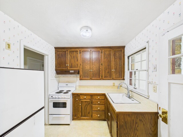 1538 8th Ave SE, Saint Cloud, MN 56304 - kitchen with electric range, wallpapered walls, a sink, light countertops, and under cabinet range hood