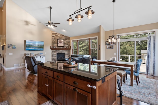 25455 145th St NW, Zimmerman, MN 55398 - kitchen featuring a ceiling fan, a stone fireplace, dark wood finished floors, decorative light fixtures, and a kitchen island