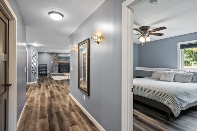 25455 145th St NW, Zimmerman, MN 55398 - bedroom featuring dark wood-style floors, a textured ceiling, a fireplace, and baseboards