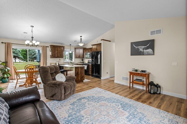 783 Park Brook Rd NW, Isanti, MN 55040 - living room featuring a chandelier, light wood finished floors, baseboards, and vaulted ceiling