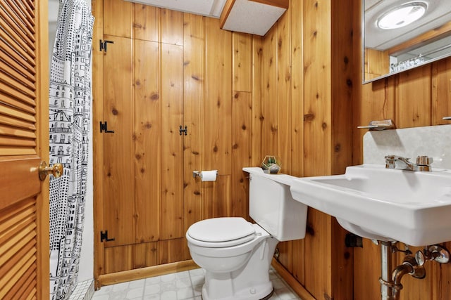 7417 Colfax Ave S, Richfield, MN 55423 - bathroom featuring toilet, wooden walls, tile patterned floors, and a sink