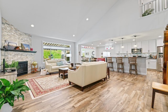 1884 Alexander Rd NE, Rochester, MN 55906 - living area featuring high vaulted ceiling, light wood-type flooring, a stone fireplace, and recessed lighting