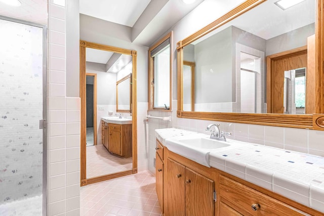 5313 Birchcrest Dr, Edina, MN 55436 - bathroom featuring tile walls, two vanities, a shower stall, tile patterned flooring, and a wainscoted wall