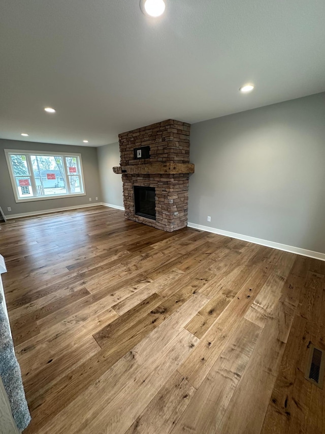 1911 Johnson St, Albert Lea, MN 56007 - unfurnished living room with hardwood / wood-style floors, a stone fireplace, recessed lighting, and baseboards