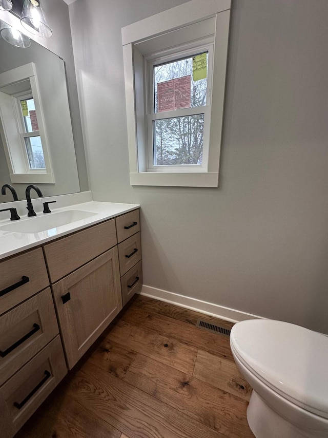 1911 Johnson St, Albert Lea, MN 56007 - bathroom featuring wood finished floors, toilet, vanity, and plenty of natural light