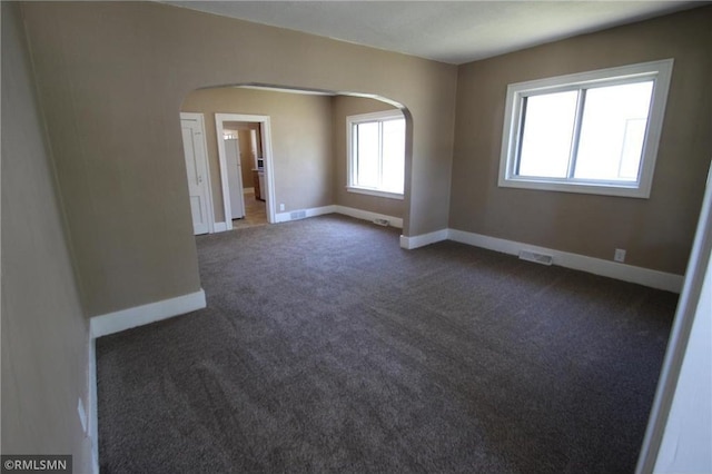 132 4th Ave N, Waite Park, MN 56387 - empty room with arched walkways, baseboards, and dark colored carpet