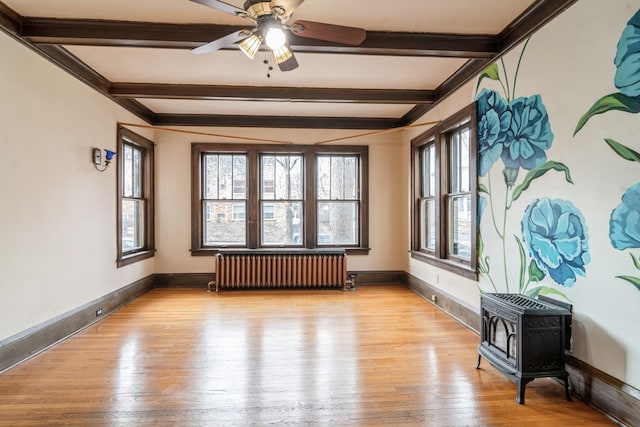 2545 Bryant Ave S Unit 1, Minneapolis, MN 55405 - empty room with radiator, beamed ceiling, a wood stove, light wood-style floors, and ceiling fan