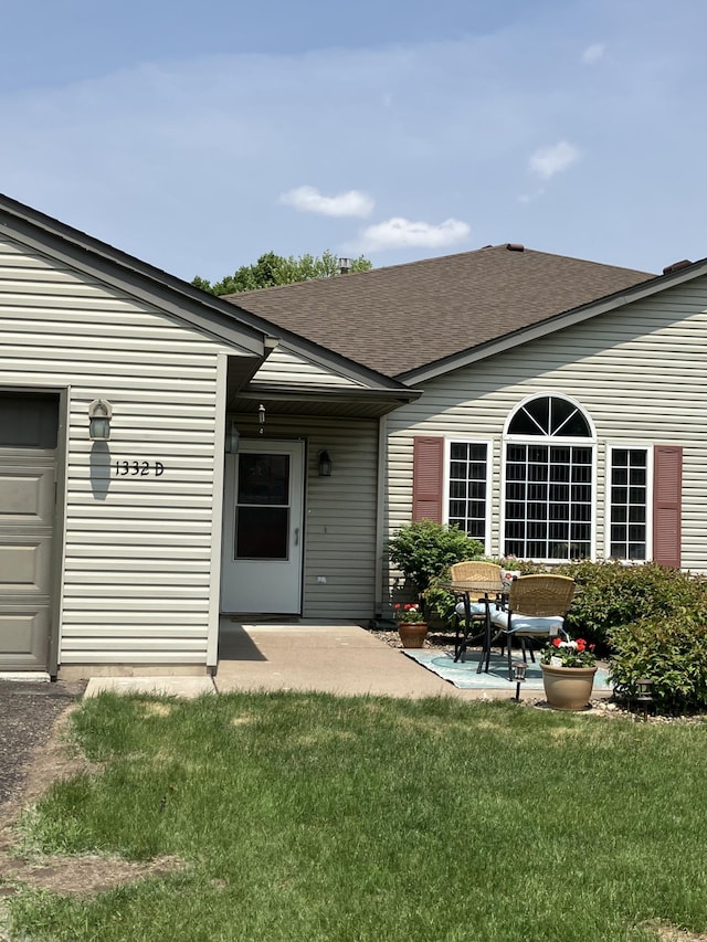 1332D Carriage Dr, Hudson, WI 54016 - back of house featuring roof with shingles, a yard, a patio area, and a garage