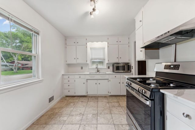 225 7th Ave NE, Osseo, MN 55369 - kitchen featuring stainless steel appliances, light countertops, white cabinetry, custom range hood, and a sink