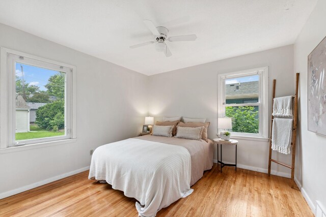 225 7th Ave NE, Osseo, MN 55369 - bedroom featuring multiple windows, light wood-type flooring, baseboards, and a ceiling fan