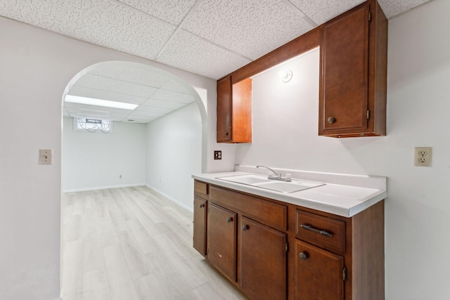 225 7th Ave NE, Osseo, MN 55369 - kitchen with a paneled ceiling, a sink, arched walkways, light countertops, and light wood-style flooring