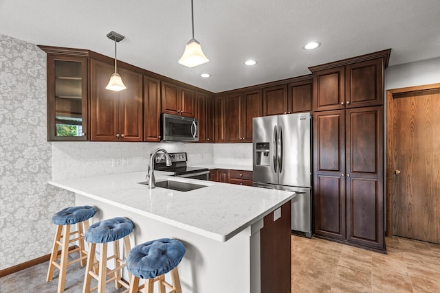 7582 Ojibway Park Bay, Woodbury, MN 55125 - kitchen featuring appliances with stainless steel finishes, wallpapered walls, a peninsula, a breakfast bar, and decorative light fixtures